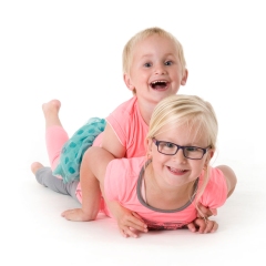Niestadt-fotografie-Schoonhoven-studio-shoot-met-twee-zusjes-samen-liggend-op-een-witte-achtergrond
