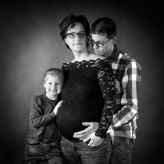Niestadt-Fotografie-Schoonhoven-zwangerschaps-shoot-sfeervol-licht-tegen-zwarte-achtergrond-in-zwart-wit-met-vader-en-dochter