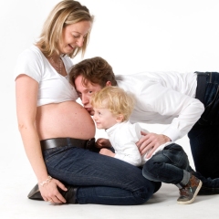 Niestadt-Fotografie-Schoonhoven-zwangerschaps-shoot-tegen-witte-achtergrond-met-man-en-dochter-die-samen-een-kusje-geven
